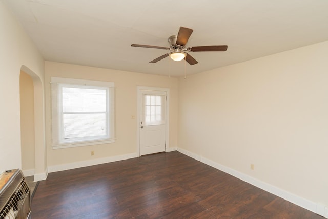 spare room with heating unit, dark hardwood / wood-style floors, and ceiling fan