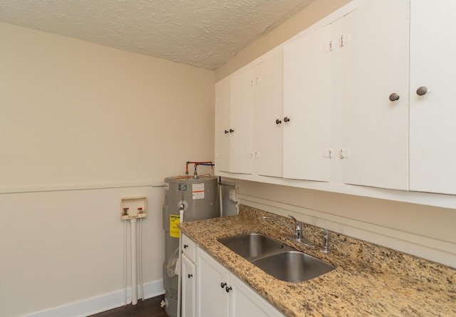 kitchen featuring sink, water heater, white cabinetry, light stone countertops, and a textured ceiling