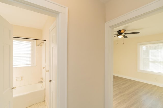 bathroom with wood-type flooring, ceiling fan, and tiled shower / bath