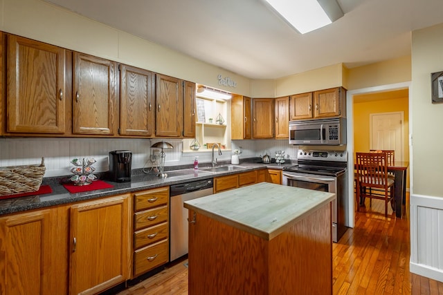 kitchen with stainless steel appliances, wood-type flooring, sink, and a kitchen island