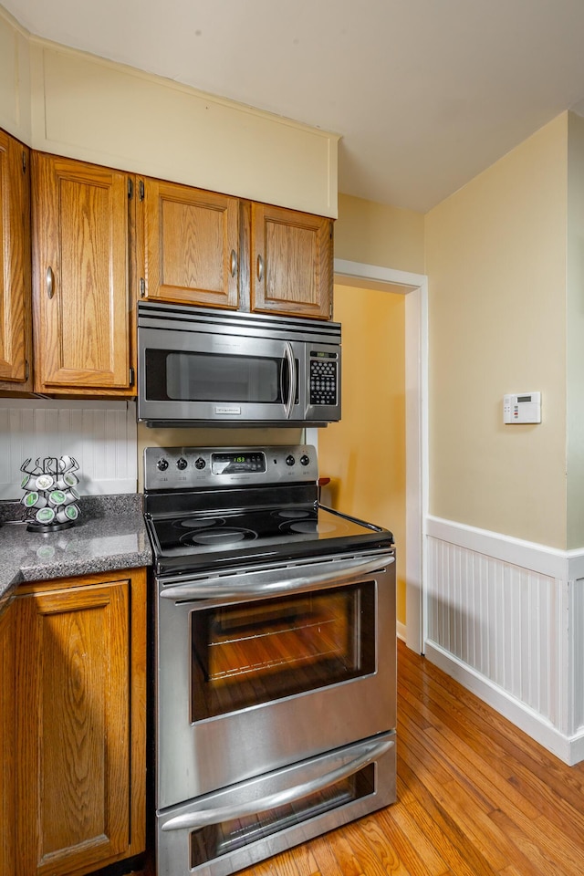 kitchen with appliances with stainless steel finishes and light hardwood / wood-style flooring