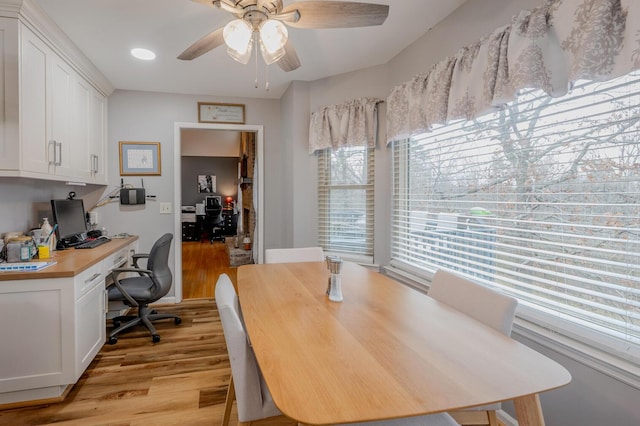 dining area with ceiling fan, built in desk, and light wood-type flooring