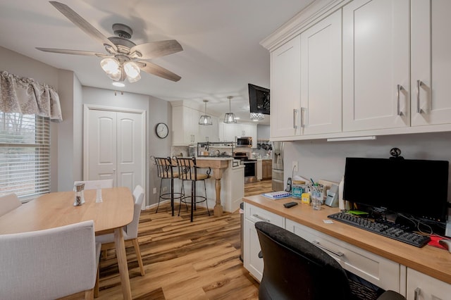 office with light hardwood / wood-style flooring, built in desk, and ceiling fan