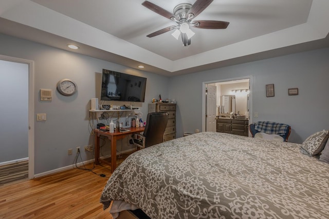 bedroom with a raised ceiling, ceiling fan, and light hardwood / wood-style flooring