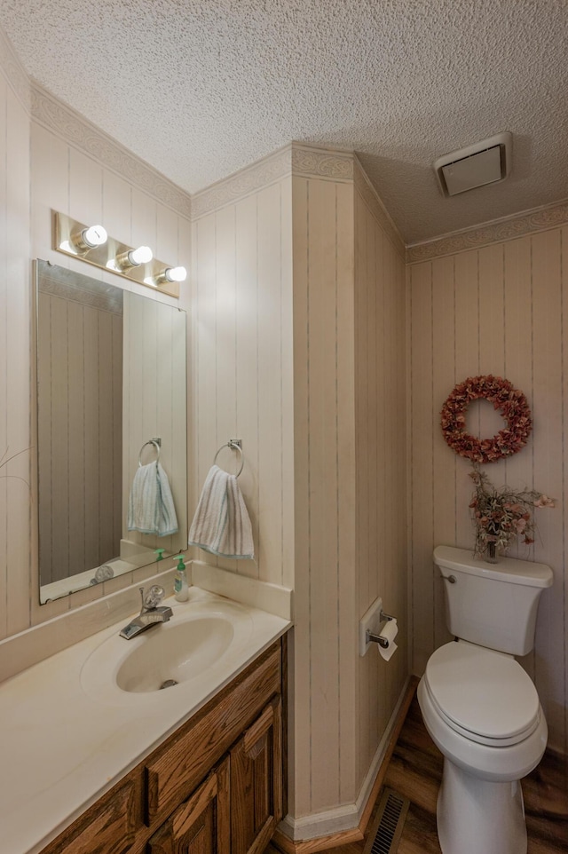 bathroom with vanity, hardwood / wood-style floors, wooden walls, and toilet