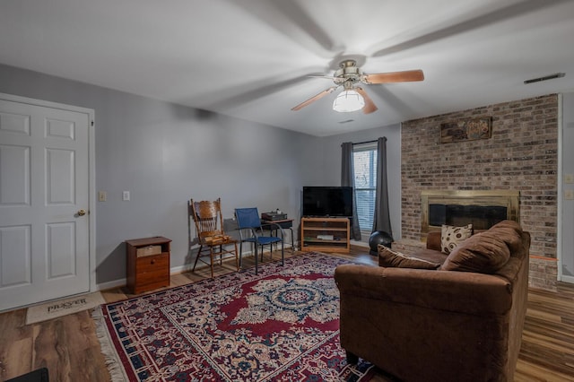 living room featuring a brick fireplace, hardwood / wood-style floors, and ceiling fan