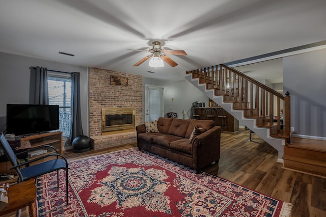 living room featuring ceiling fan, wood-type flooring, and a fireplace