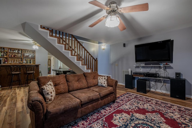 living room featuring ceiling fan, bar area, and hardwood / wood-style floors