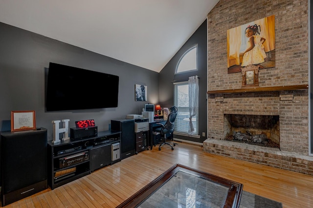 living room featuring a brick fireplace, wood-type flooring, and high vaulted ceiling