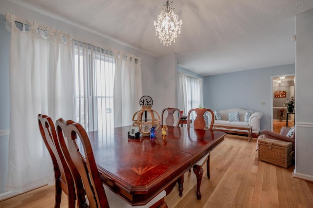 dining area featuring a notable chandelier, plenty of natural light, light hardwood / wood-style floors, and a textured ceiling