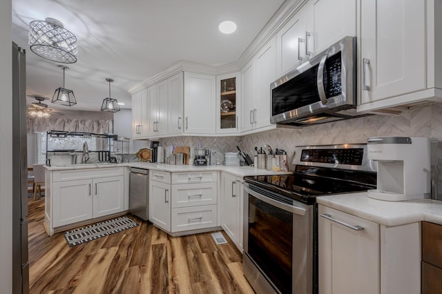 kitchen featuring hanging light fixtures, hardwood / wood-style floors, white cabinets, and appliances with stainless steel finishes