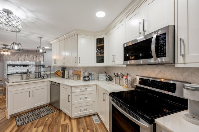 kitchen with sink, decorative light fixtures, light hardwood / wood-style flooring, stainless steel appliances, and white cabinets