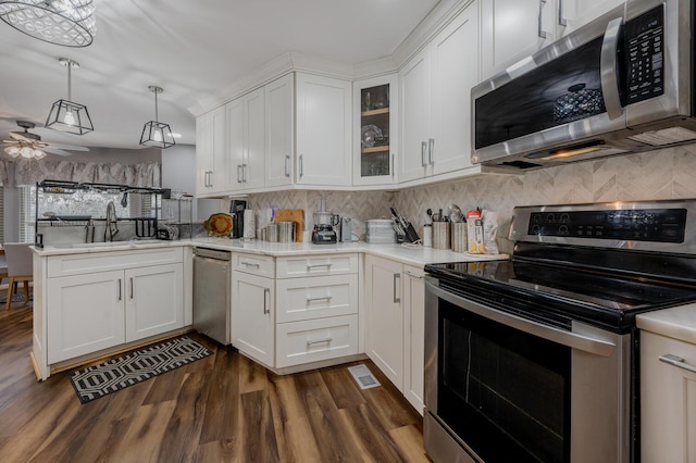 kitchen featuring pendant lighting, sink, appliances with stainless steel finishes, white cabinets, and kitchen peninsula