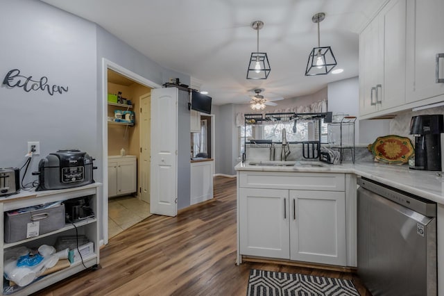 kitchen featuring dishwasher, sink, pendant lighting, and white cabinets