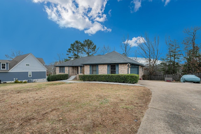 ranch-style home with a garage, a front yard, and central air condition unit