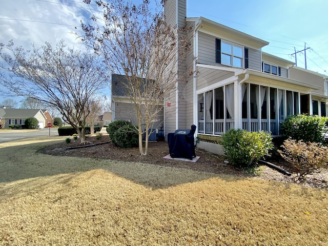 view of side of property featuring a lawn and a sunroom