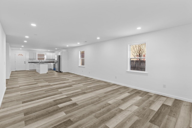 unfurnished living room with sink and light hardwood / wood-style floors