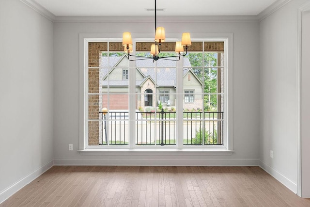 unfurnished dining area with crown molding, a chandelier, a healthy amount of sunlight, and light wood-type flooring