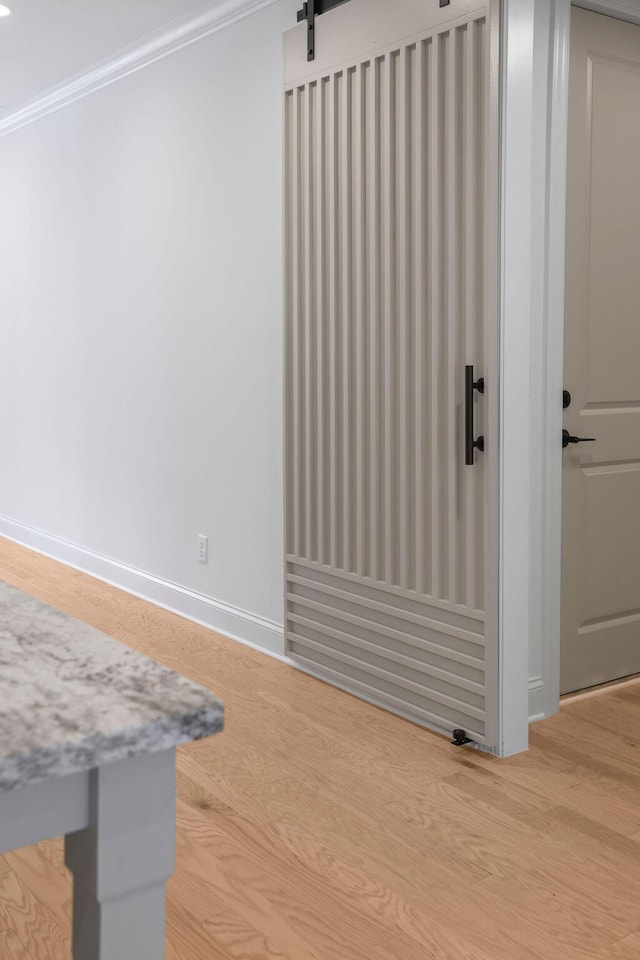 interior space with crown molding, a barn door, and hardwood / wood-style flooring