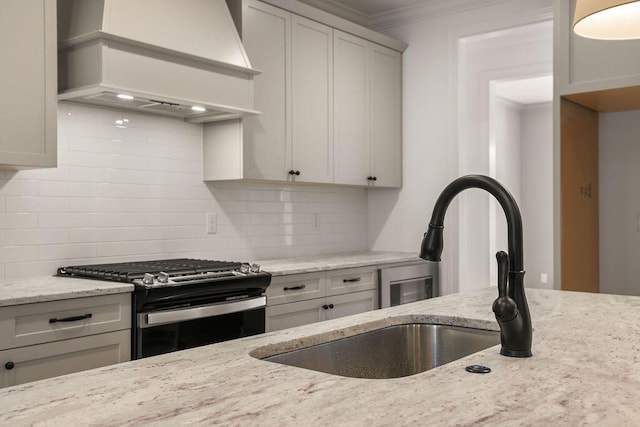 kitchen with tasteful backsplash, premium range hood, light stone countertops, and stainless steel range with gas stovetop