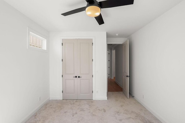 unfurnished bedroom featuring light carpet, a closet, and ceiling fan