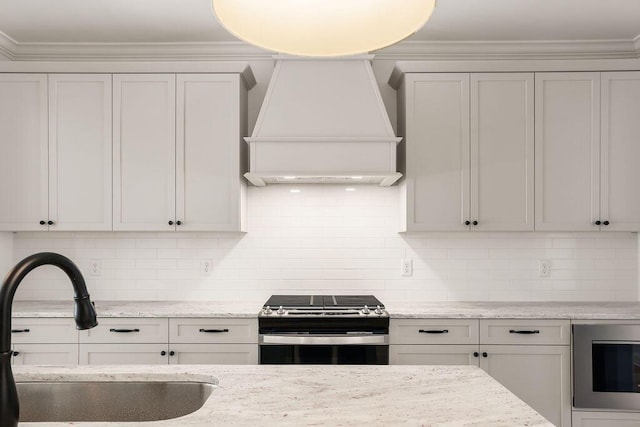 kitchen with tasteful backsplash, built in microwave, sink, custom range hood, and stainless steel range with gas stovetop