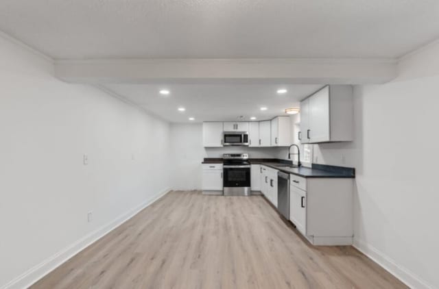 kitchen with sink, crown molding, appliances with stainless steel finishes, white cabinetry, and light hardwood / wood-style floors