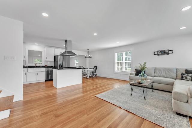 living area with recessed lighting, a notable chandelier, light wood-style flooring, and baseboards