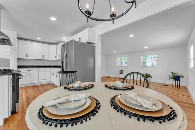 dining space featuring light wood finished floors, baseboards, an inviting chandelier, and recessed lighting