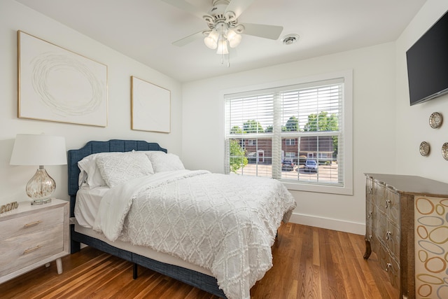 bedroom featuring a ceiling fan, visible vents, baseboards, and wood finished floors