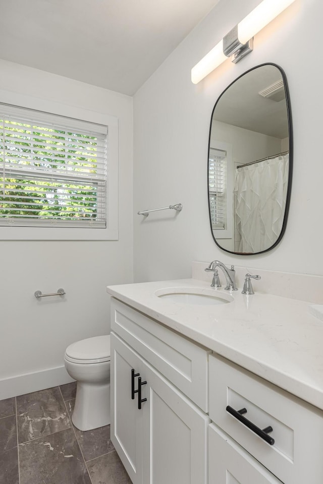 bathroom featuring toilet, baseboards, and vanity