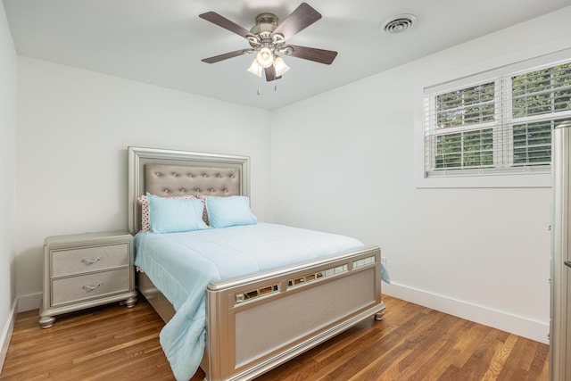 bedroom with baseboards, visible vents, ceiling fan, and wood finished floors