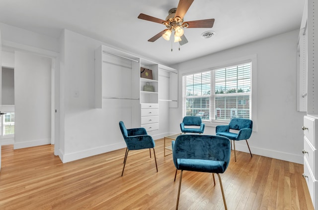 living area with light wood finished floors, baseboards, visible vents, and ceiling fan