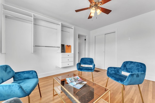 sitting room with baseboards, light wood-style flooring, and a ceiling fan