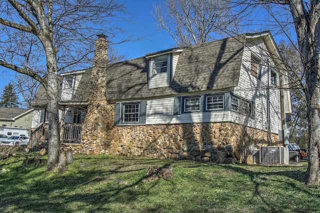 view of side of home featuring a yard and central AC