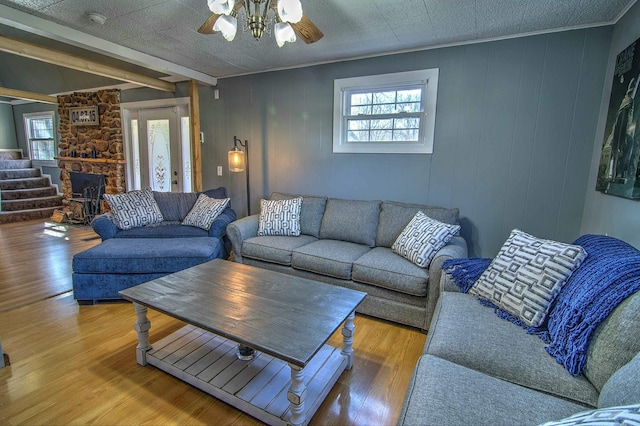 living room with hardwood / wood-style flooring, ceiling fan, wooden walls, and beamed ceiling