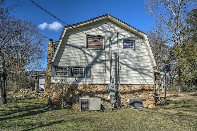 view of side of property featuring cooling unit and a yard