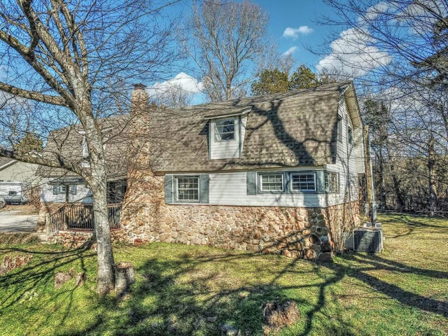 view of side of home with central AC and a yard