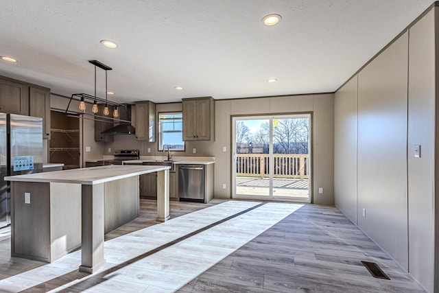 kitchen featuring sink, a center island, light hardwood / wood-style flooring, appliances with stainless steel finishes, and pendant lighting