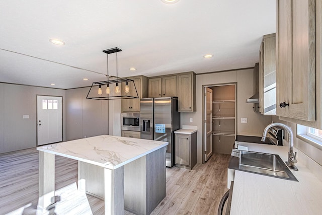 kitchen featuring sink, hanging light fixtures, stainless steel appliances, a center island, and light wood-type flooring