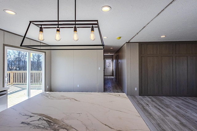 unfurnished bedroom with wooden walls, dark hardwood / wood-style floors, access to outside, and a textured ceiling