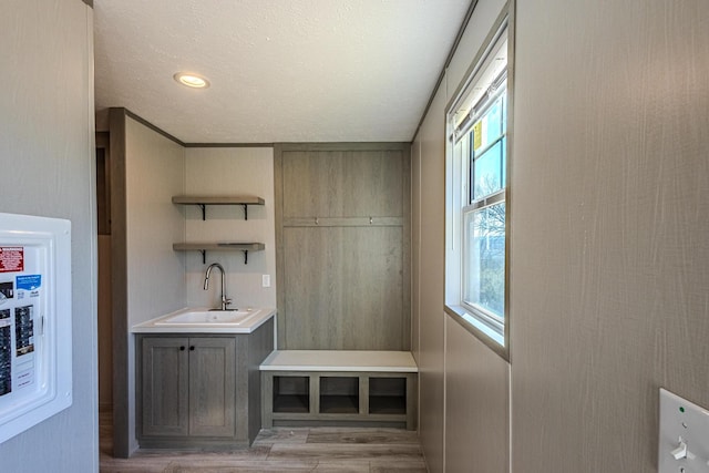 mudroom with sink, a textured ceiling, and light hardwood / wood-style floors