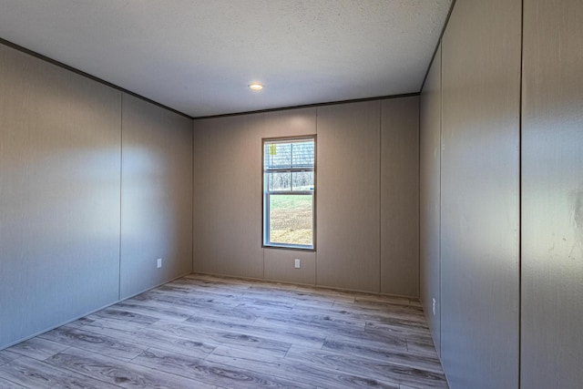 spare room with ornamental molding, light hardwood / wood-style floors, and a textured ceiling