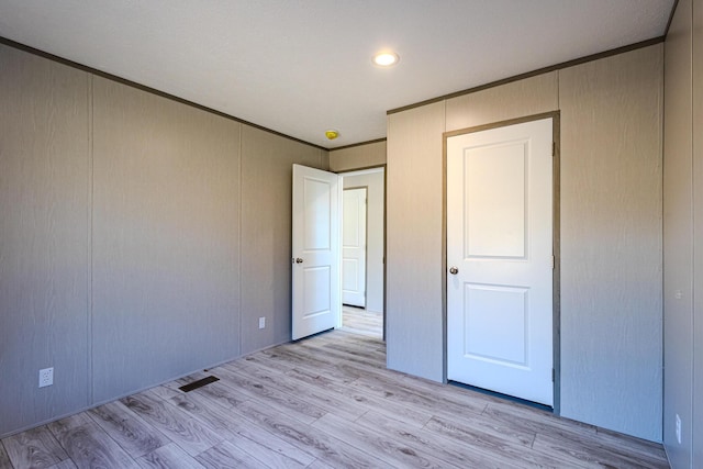 unfurnished bedroom with ornamental molding and light hardwood / wood-style flooring