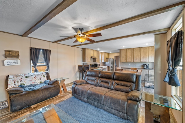 living room featuring beamed ceiling, ceiling fan, hardwood / wood-style floors, and a textured ceiling