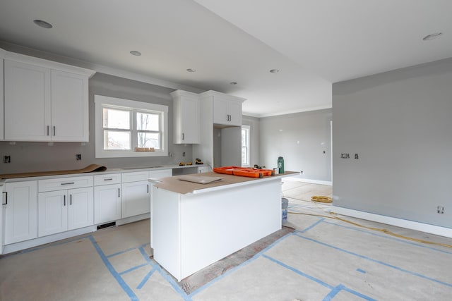 kitchen featuring white cabinetry, ornamental molding, and a center island