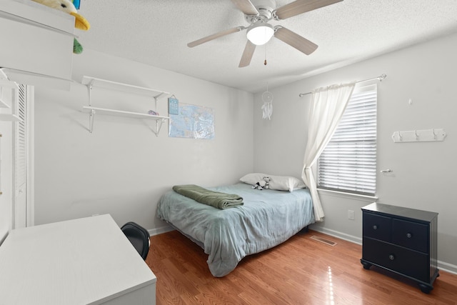 bedroom with wood-type flooring, a textured ceiling, and ceiling fan