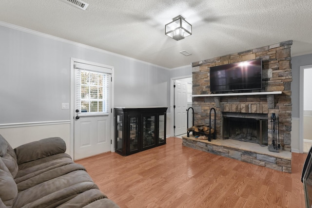 living room with a stone fireplace, light hardwood / wood-style floors, and a textured ceiling