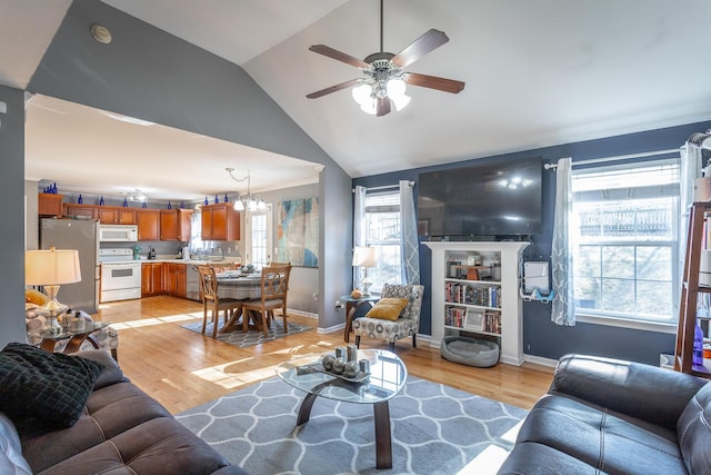 living room with lofted ceiling, ceiling fan with notable chandelier, plenty of natural light, and light hardwood / wood-style floors