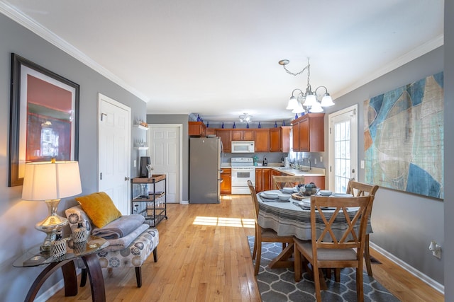 dining space featuring crown molding, a notable chandelier, and light hardwood / wood-style flooring